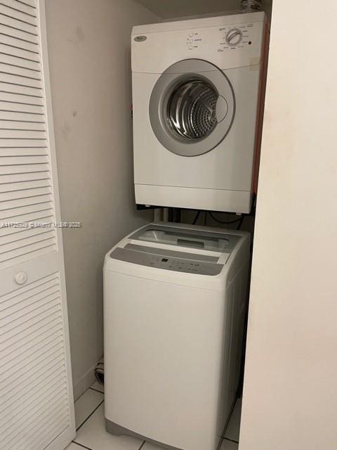 clothes washing area with stacked washing maching and dryer and light tile patterned floors