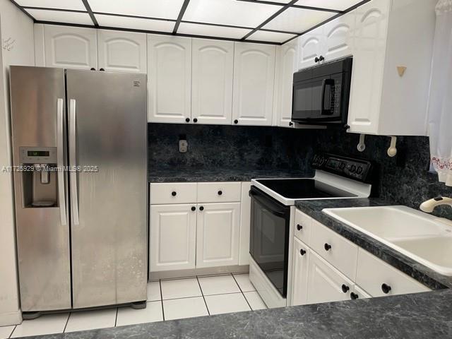 kitchen featuring stainless steel fridge, white cabinetry, electric stove, and decorative backsplash