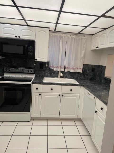 kitchen with light tile patterned floors, white dishwasher, white cabinets, electric range oven, and sink