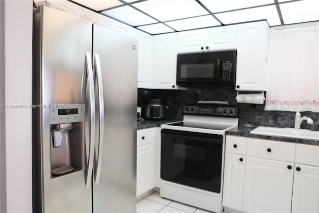 kitchen featuring electric stove, white cabinetry, and stainless steel fridge