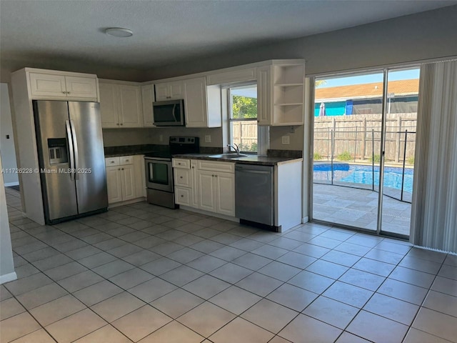 kitchen with white cabinets, appliances with stainless steel finishes, light tile patterned flooring, and sink