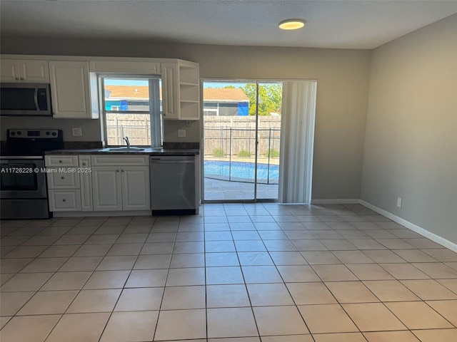 kitchen featuring appliances with stainless steel finishes, white cabinetry, light tile patterned floors, and sink