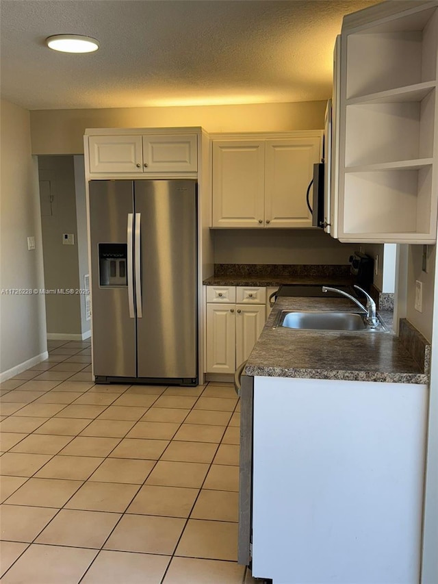 kitchen with sink, white cabinetry, light tile patterned floors, and stainless steel fridge with ice dispenser