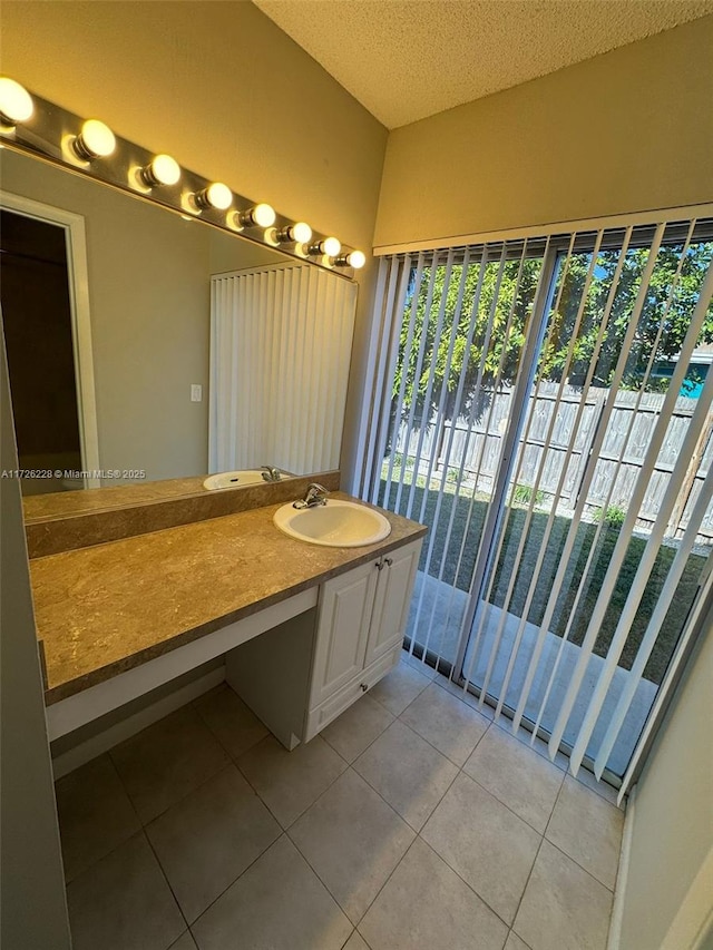 bathroom with plenty of natural light, a textured ceiling, tile patterned floors, and sink