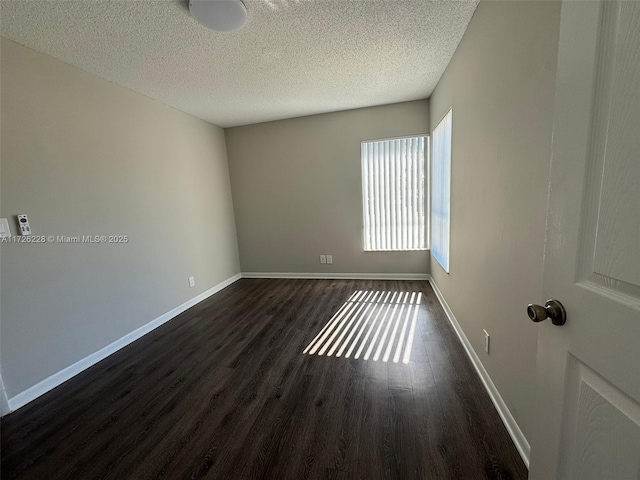 spare room featuring a textured ceiling and dark hardwood / wood-style floors