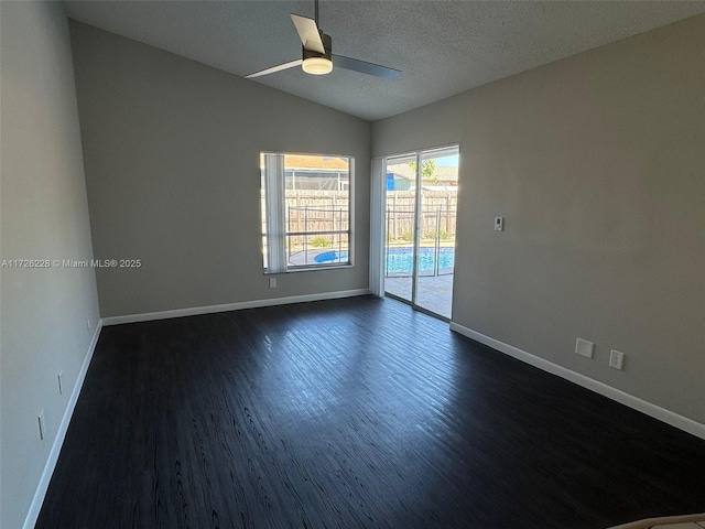 empty room featuring lofted ceiling, dark wood-type flooring, a textured ceiling, and ceiling fan