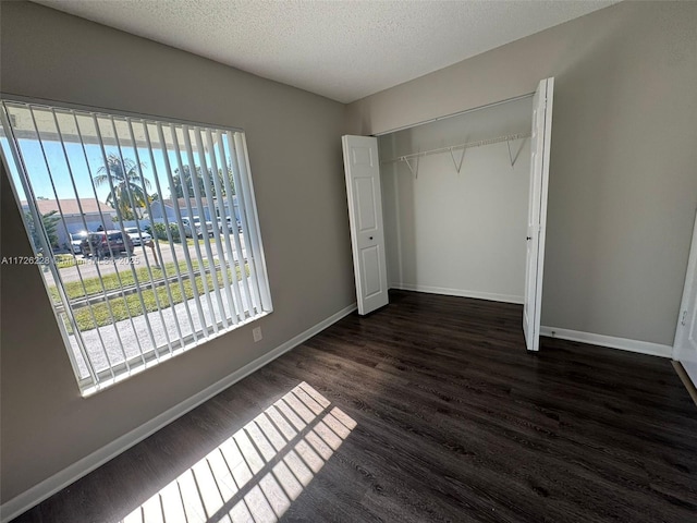 unfurnished bedroom with a textured ceiling, a closet, and dark hardwood / wood-style flooring