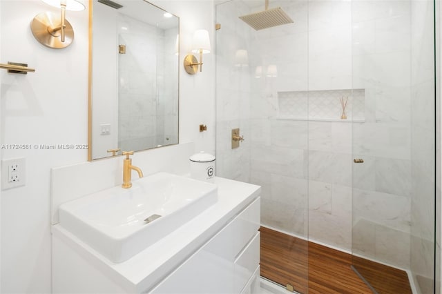 bathroom with tiled shower, hardwood / wood-style flooring, and vanity