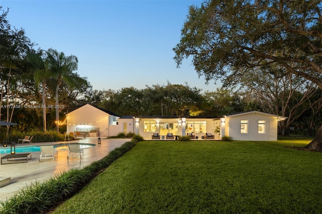 back house at dusk with a yard and a patio