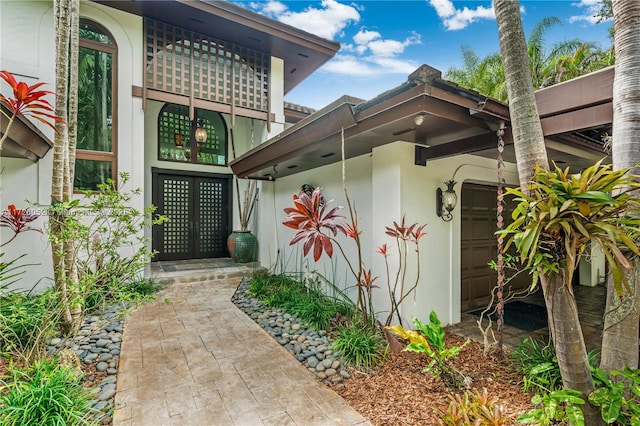 view of exterior entry featuring a balcony, french doors, and a garage