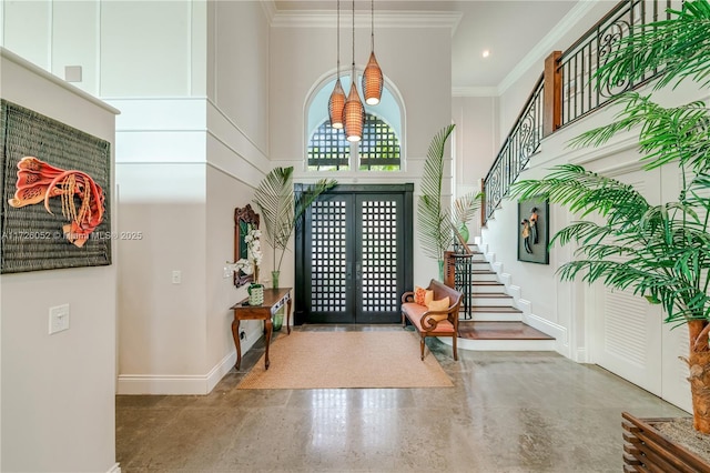 entrance foyer with a towering ceiling, french doors, and crown molding