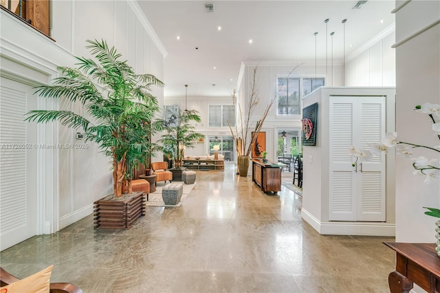 foyer entrance featuring a towering ceiling and ornamental molding