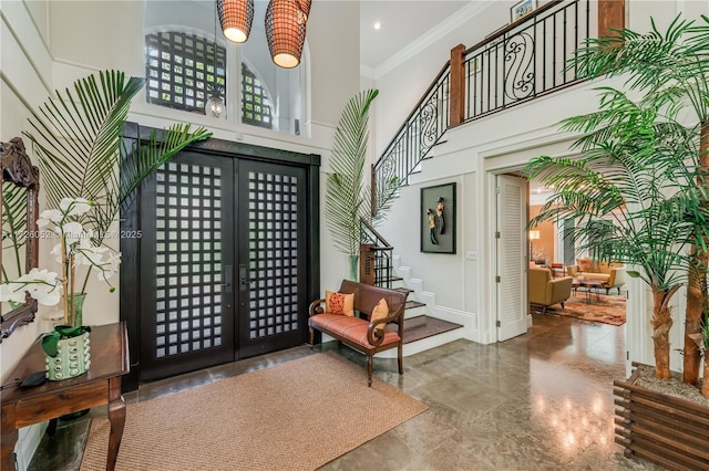 foyer featuring a high ceiling, french doors, and crown molding