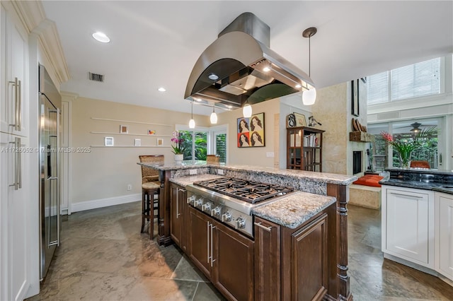 kitchen featuring island range hood, a center island, decorative light fixtures, stainless steel appliances, and a kitchen breakfast bar