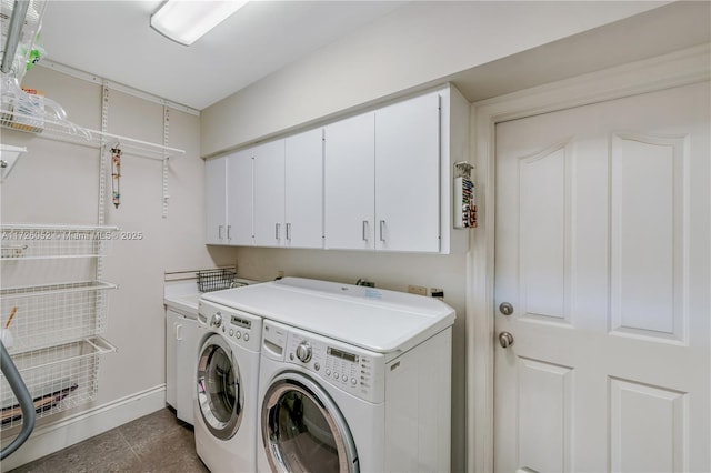 clothes washing area with washer and dryer, cabinets, and dark tile patterned flooring