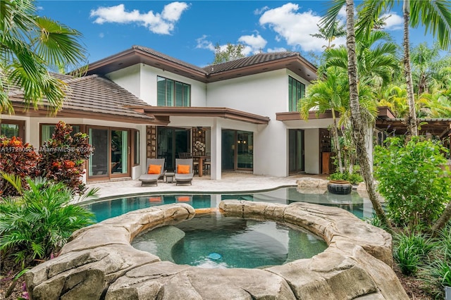 rear view of property featuring a swimming pool with hot tub and a patio area