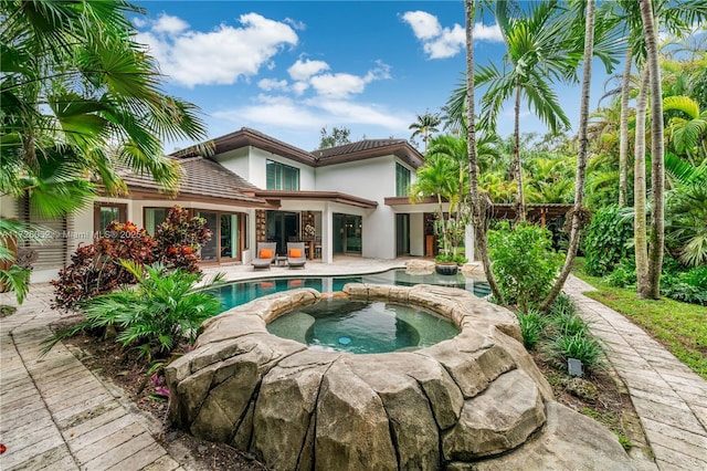 rear view of house featuring a pool with hot tub and a patio