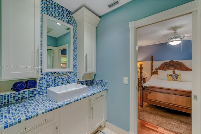 bathroom with ceiling fan, vanity, decorative backsplash, and wood-type flooring