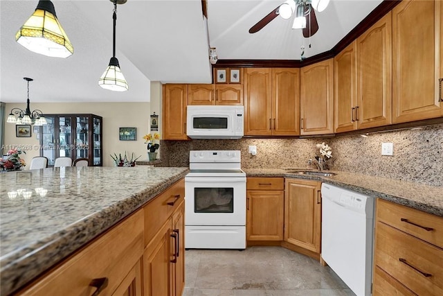 kitchen featuring white appliances, light stone counters, hanging light fixtures, backsplash, and sink