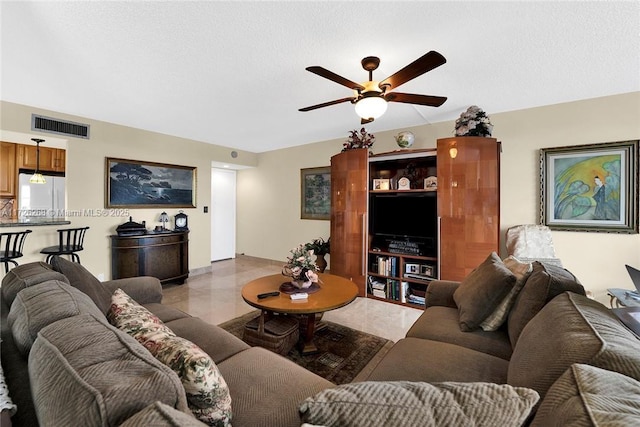 living room featuring a textured ceiling and ceiling fan