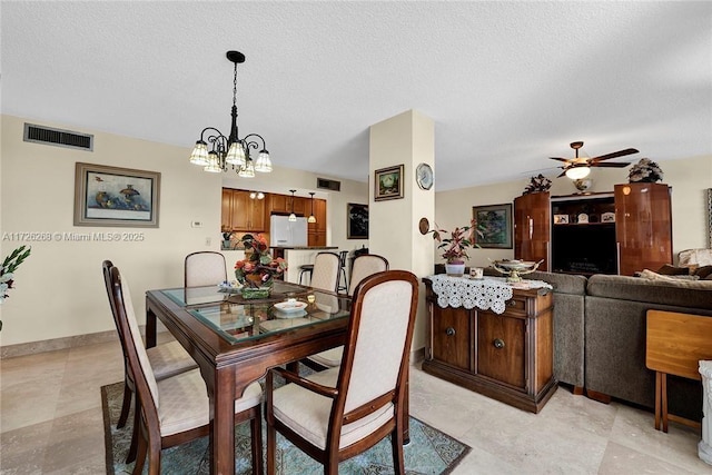 dining space with ceiling fan with notable chandelier and a textured ceiling