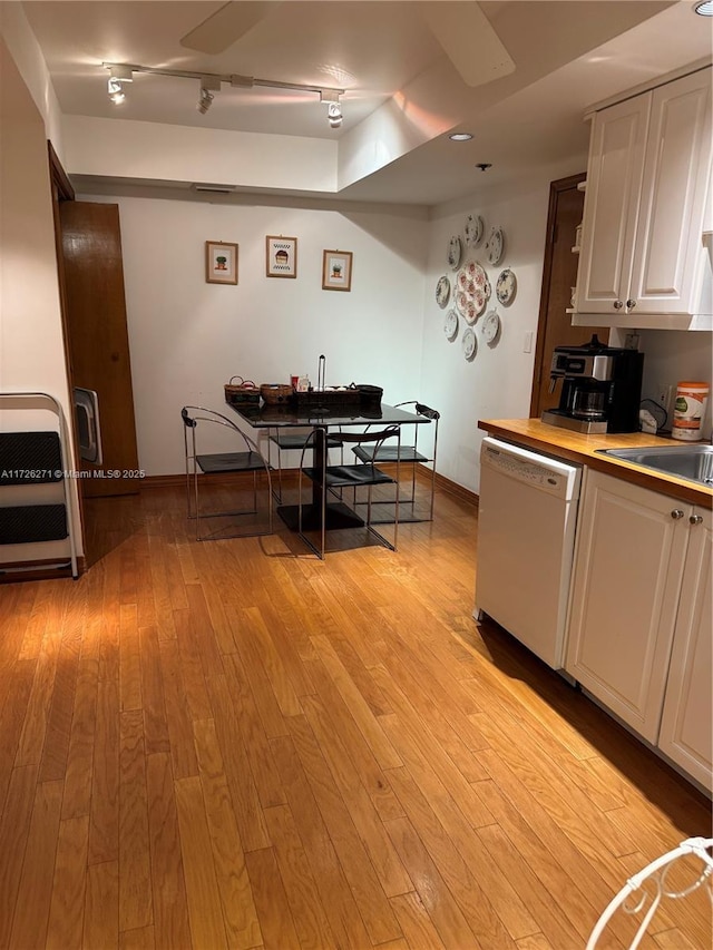 kitchen featuring sink, light wood-type flooring, white cabinetry, and white dishwasher