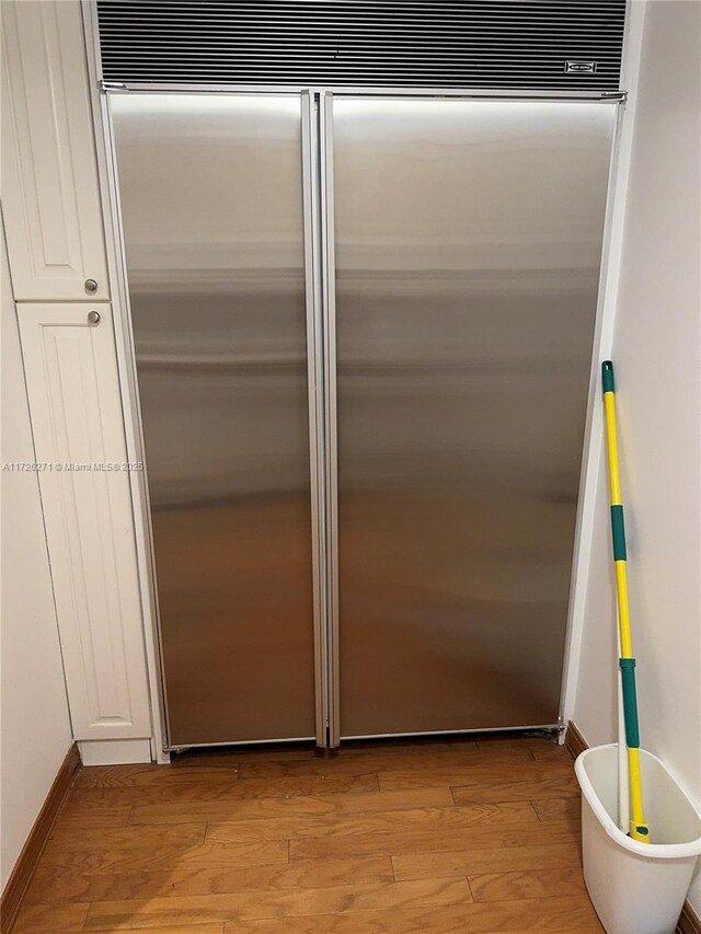 interior space with built in fridge, white cabinetry, and light hardwood / wood-style flooring