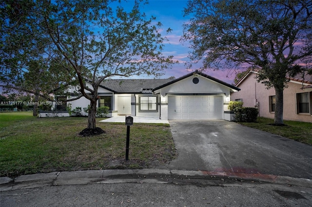 single story home featuring a garage and a yard