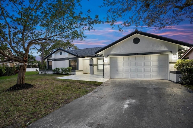 single story home with a garage and a lawn