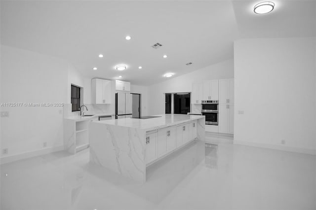 kitchen with white cabinetry, fridge, lofted ceiling, and a kitchen island