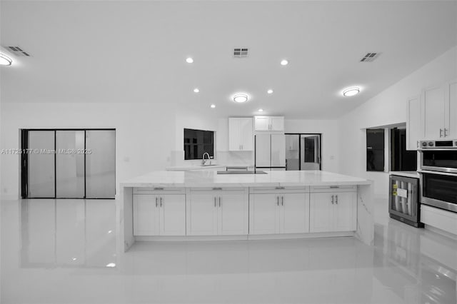 kitchen featuring white cabinetry, built in fridge, light tile patterned flooring, and light stone counters