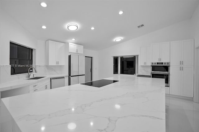 kitchen featuring sink, lofted ceiling, refrigerator, stainless steel double oven, and black electric stovetop