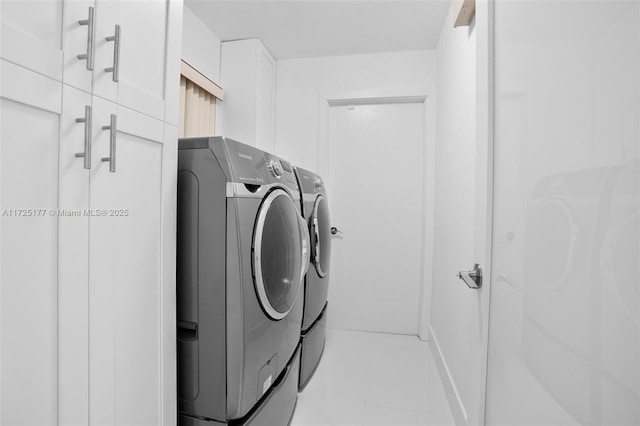 clothes washing area with washing machine and clothes dryer, light tile patterned floors, and cabinets