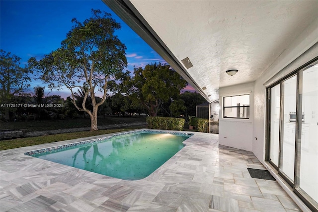 pool at dusk with a patio