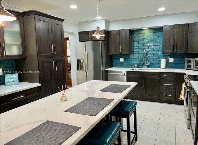 kitchen with hanging light fixtures, a breakfast bar, backsplash, appliances with stainless steel finishes, and sink