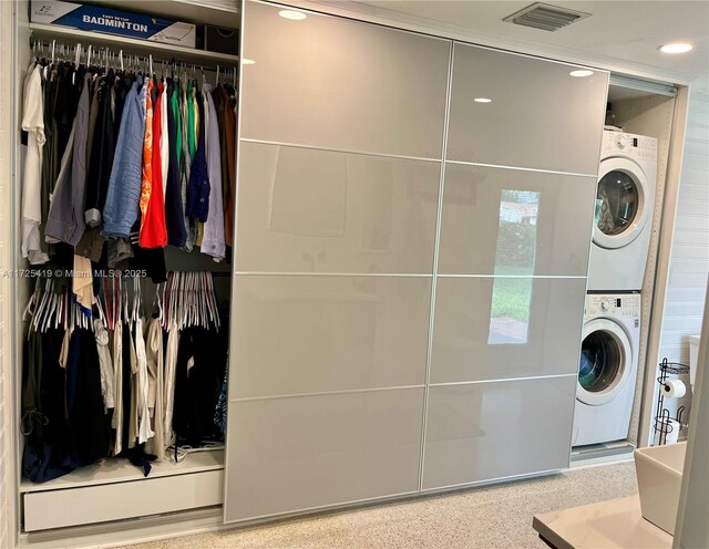 clothes washing area featuring stacked washer and clothes dryer