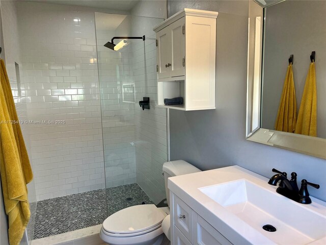 bathroom featuring toilet, vanity, and tiled shower