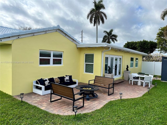 back of property featuring an outdoor fire pit, a patio area, french doors, and a lawn