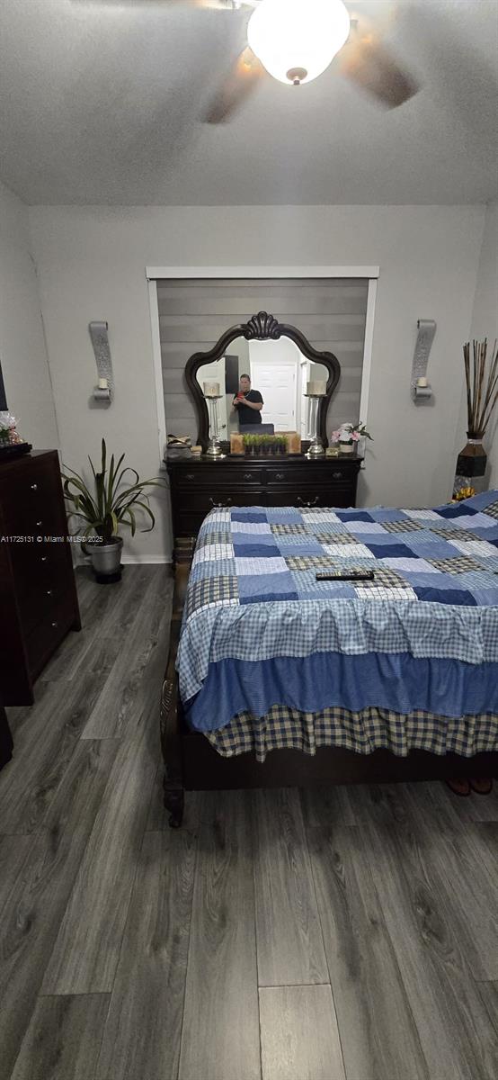 bedroom with ceiling fan, dark hardwood / wood-style flooring, and a textured ceiling