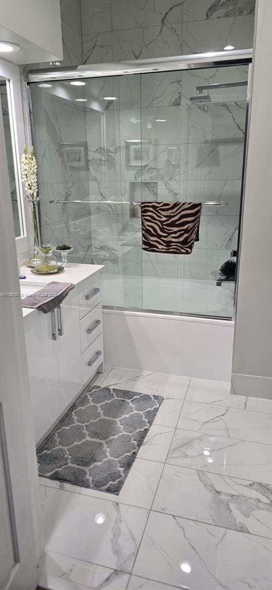 bathroom featuring shower / bath combination with glass door and vanity