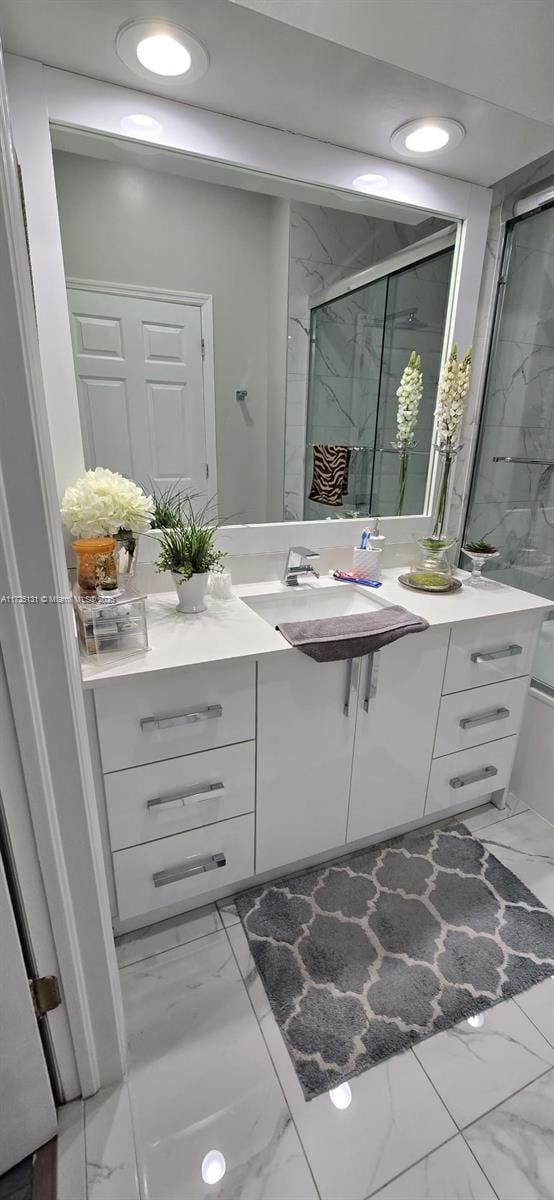 bathroom featuring a shower with door and vanity