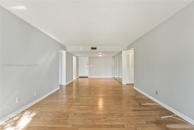 unfurnished room featuring a textured ceiling and light hardwood / wood-style floors