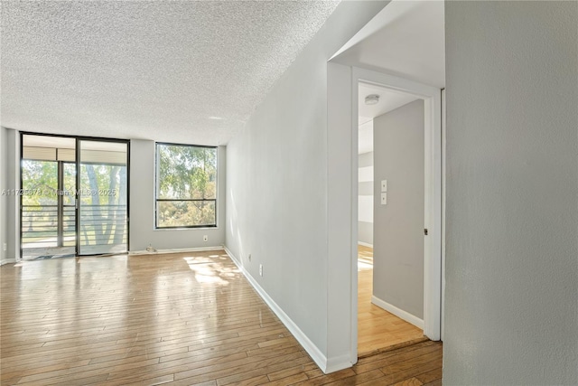 spare room with a textured ceiling, light wood-type flooring, and expansive windows