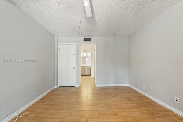 spare room with a textured ceiling, ceiling fan, and light hardwood / wood-style flooring