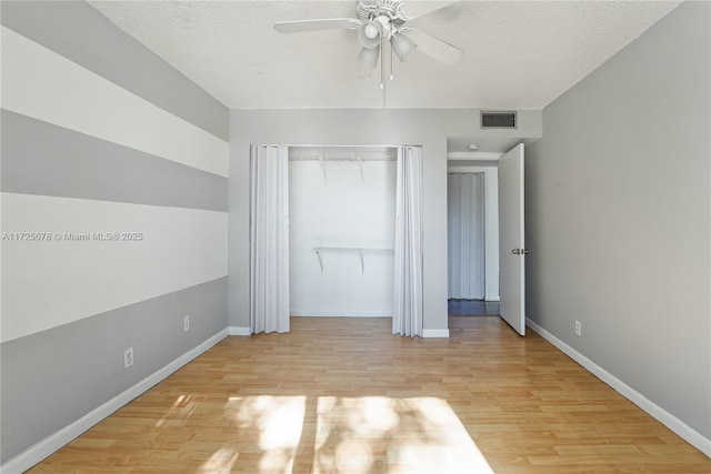 unfurnished bedroom featuring a closet, ceiling fan, a textured ceiling, and light wood-type flooring