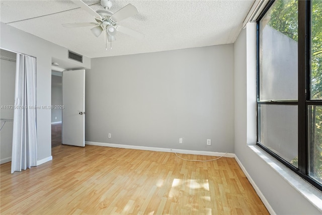 unfurnished bedroom with a textured ceiling, ceiling fan, light hardwood / wood-style flooring, and multiple windows