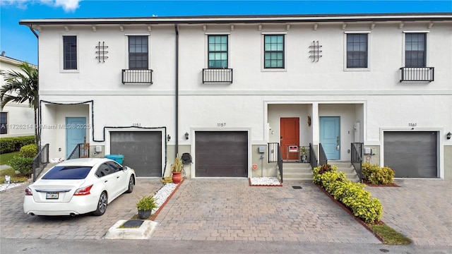 multi unit property with stucco siding, driveway, and a garage