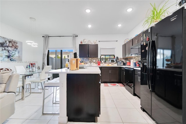 kitchen with backsplash, a kitchen breakfast bar, black appliances, and light countertops