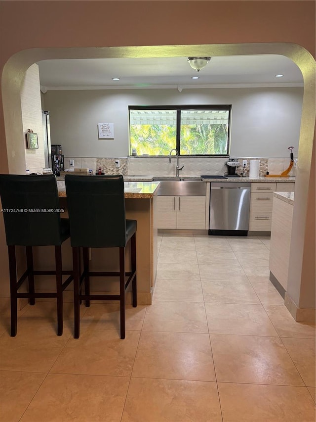 kitchen with sink, a breakfast bar, white cabinetry, and dishwasher