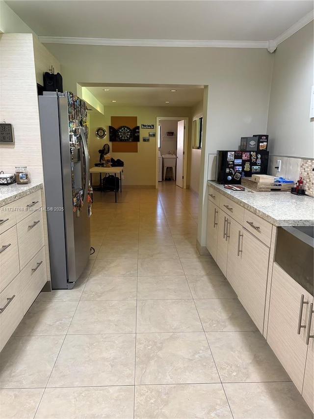 kitchen featuring ornamental molding, stainless steel fridge, decorative backsplash, and light stone countertops